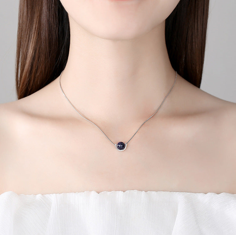 Necklace with a purple pendant worn by a model on a plain background