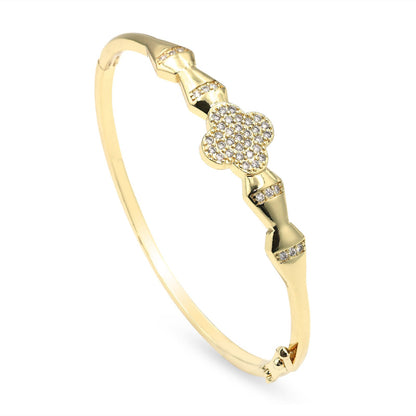 A gold bangle bracelet featuring a pavé-set four-leaf clover motif and small diamond accents, shown on a clean white background.