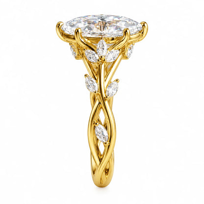 A yellow gold ring featuring a large oval-cut clear gemstone in a prong setting, with leaf-shaped accent stones along a twisted, vine-like shank, shown on a plain white background.