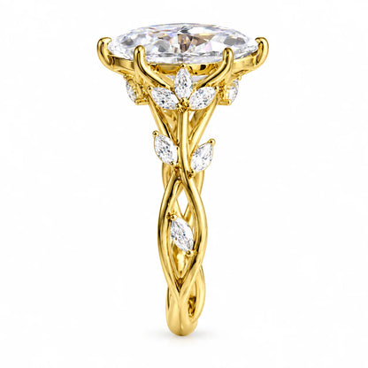 A yellow gold ring with a large oval center stone and smaller marquise-cut stones arranged like leaves and vines, shown on a plain white background.