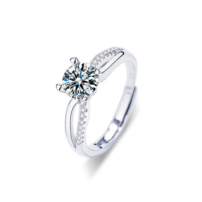 Silver ring with a large diamond and smaller diamonds on the band against a white background