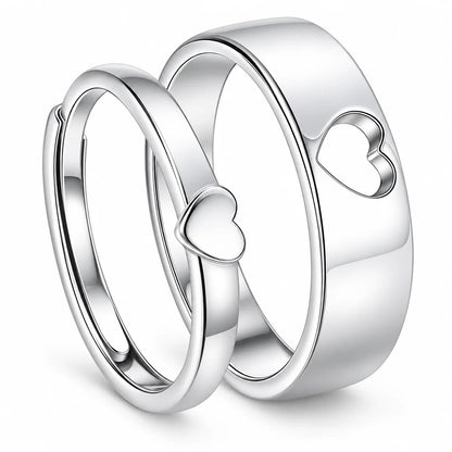 Three polished silver rings with heart motifs, including two overlapping bands with small heart cutouts and one larger band with a larger heart cutout, shown on a white background.