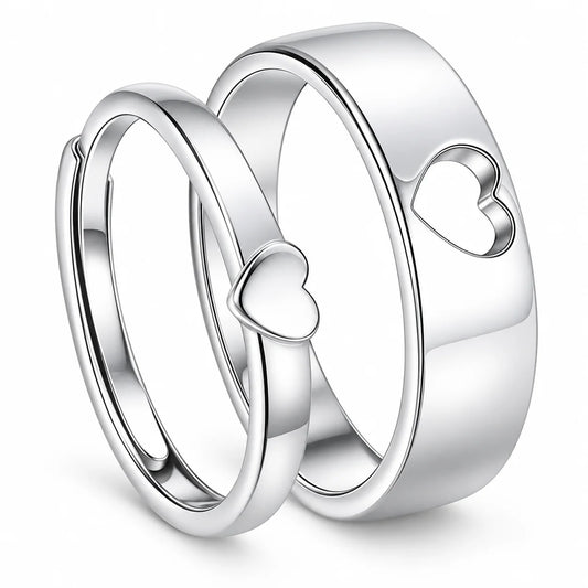 Three polished silver rings with heart motifs, including two overlapping bands with small heart cutouts and one larger band with a larger heart cutout, shown on a white background.